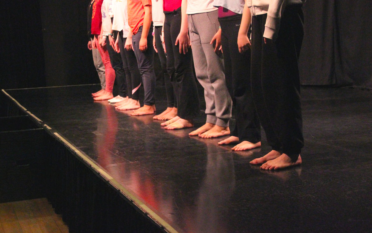 enfants faisant le salut sur le devant de la scène de théâtre. On ne voit pas leur visages
