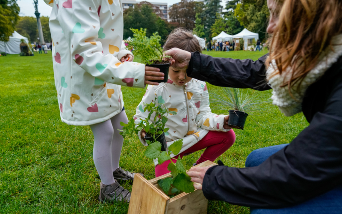 Une femme tend des plantes en pot à des enfants dans le cadre d'un atelier de jardinage