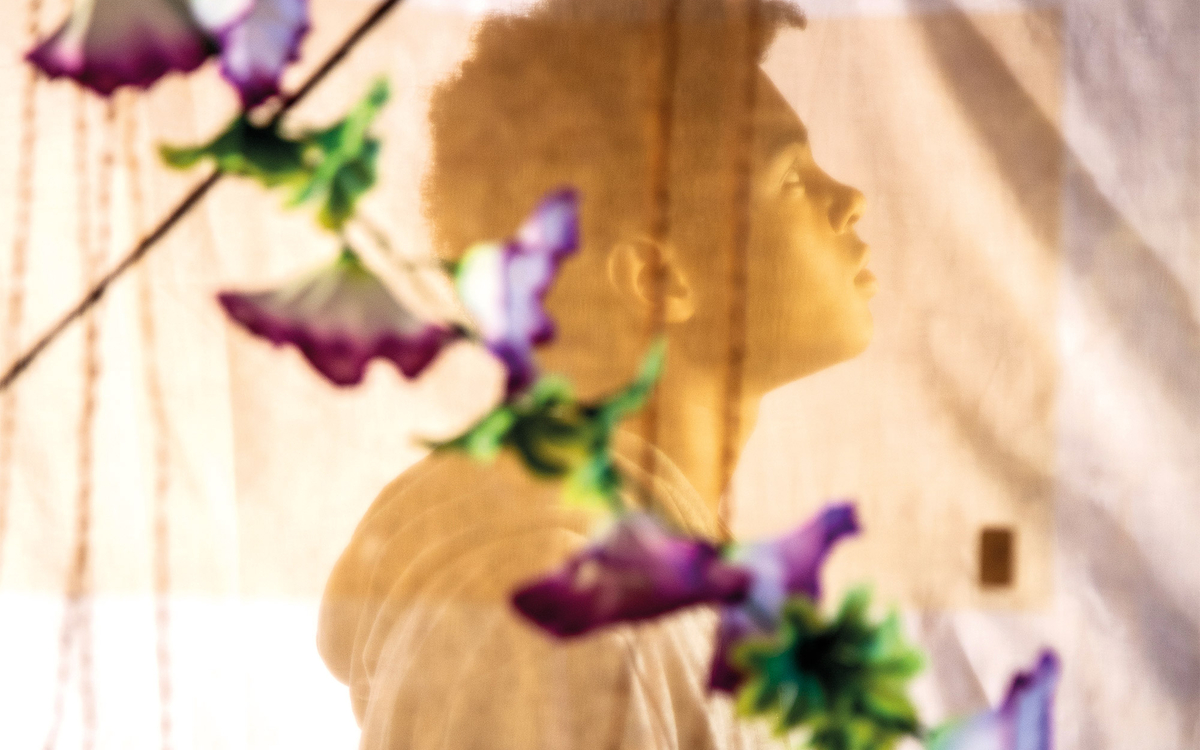 Adolescent d'environ 14 ans dans une posture de rêveuse et un décor voilé et floral