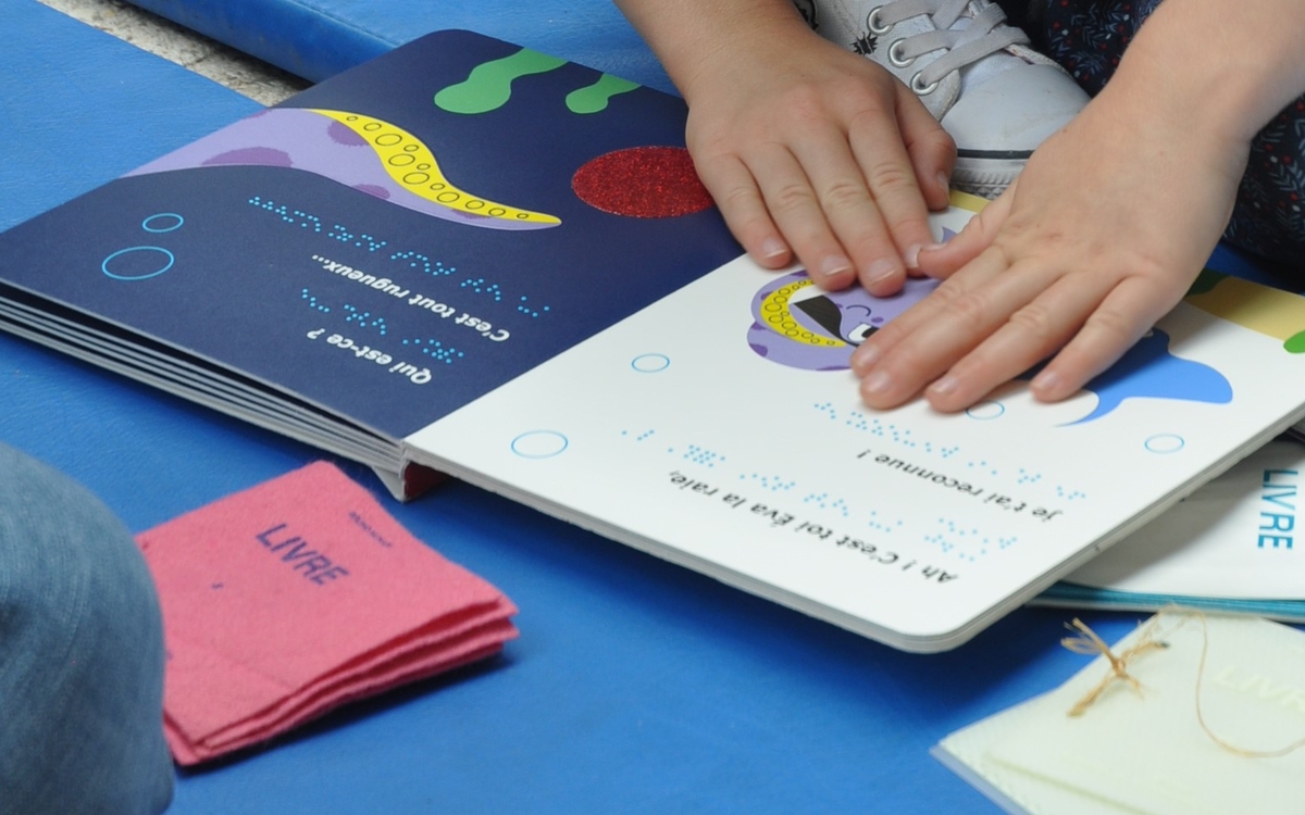 Photographie de mains d'enfants explorant un livre tactile