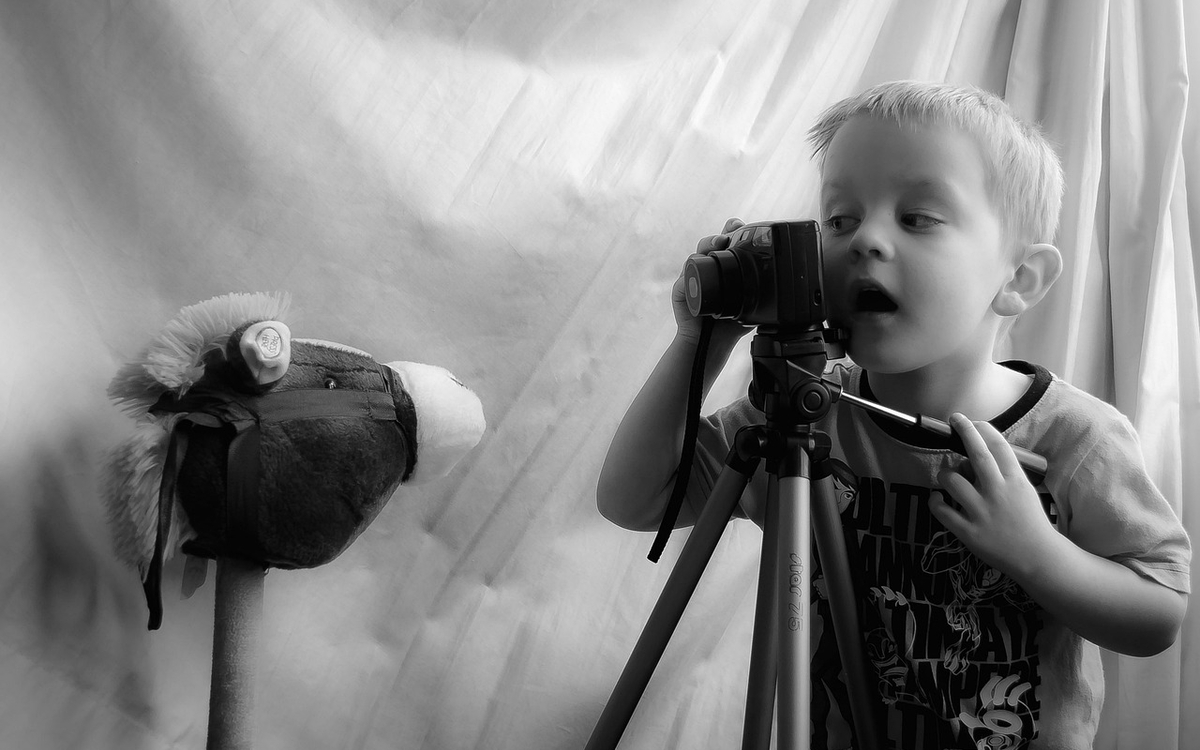 petit garçons regardant à travers une caméra son jouet qu'il est prêt à filmer