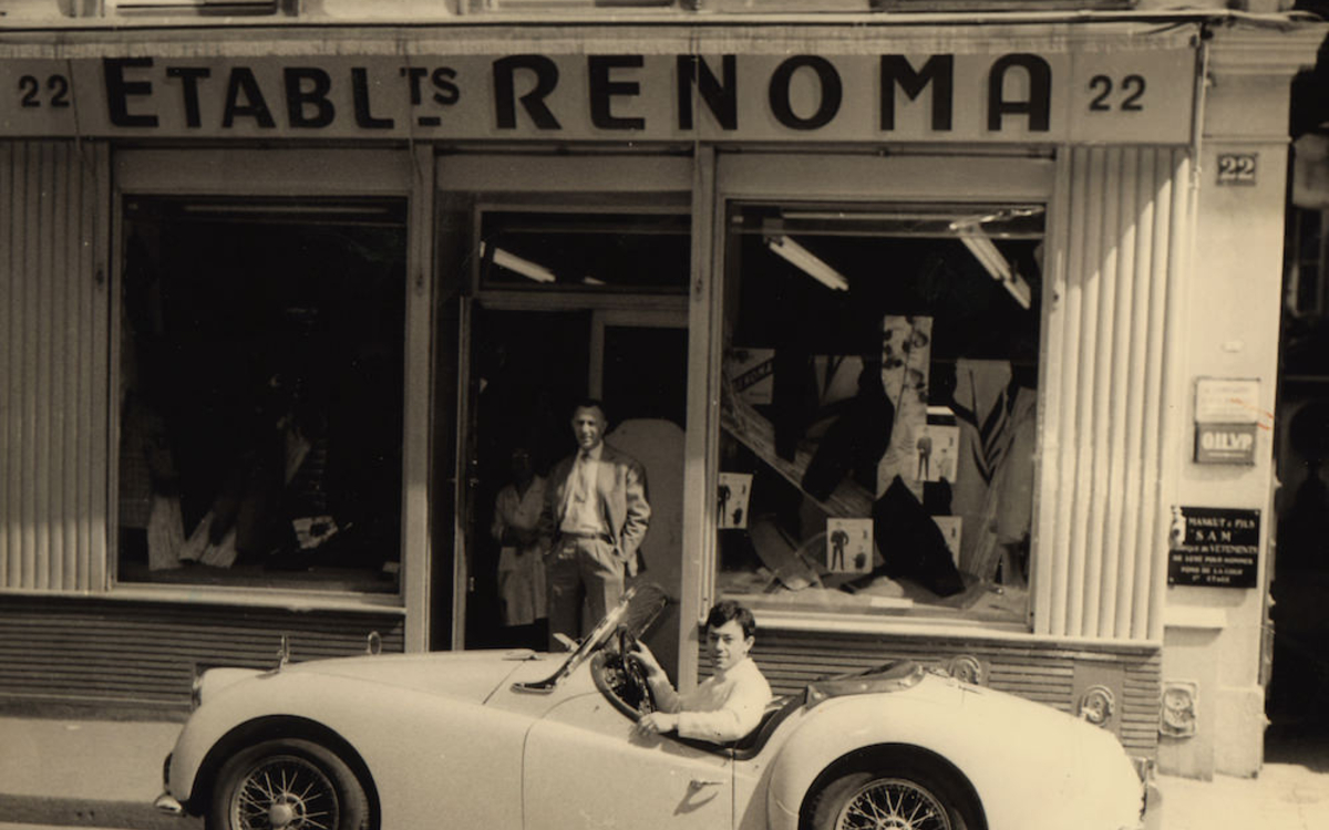 © 1 Maurice Renoma au volant de sa TR3 devant la boutique familiale, 22 rue Notre-Dame de Nazareth, 75003 Paris, 1961 _ © Archives Renoma