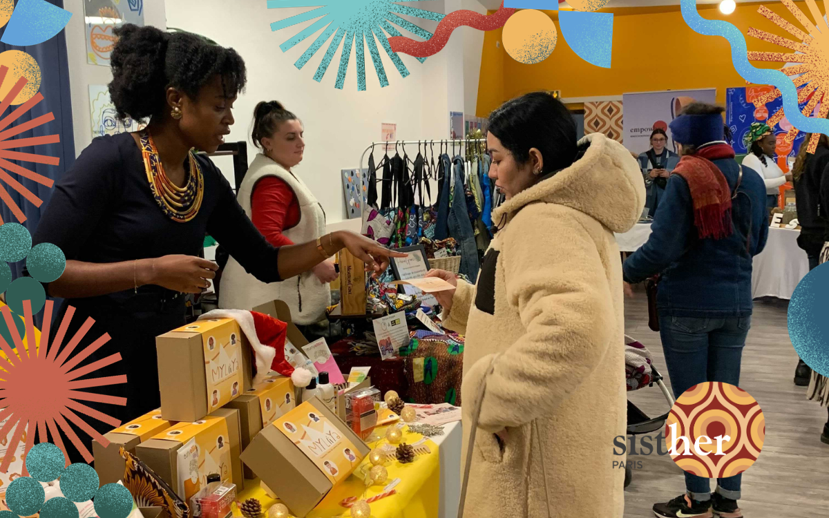 Cette image présente une entrepreneure présentant ses produits à une clientes lors d'un marché de noël