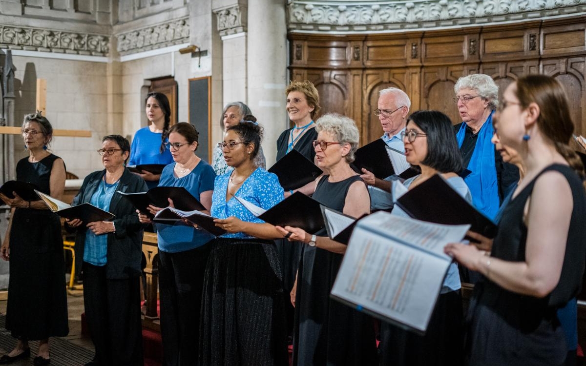 Photo représentant l'ensemble vocal Alma Musica, composé de femmes et d'hommes en noir et bleu, et chantant dans une église.