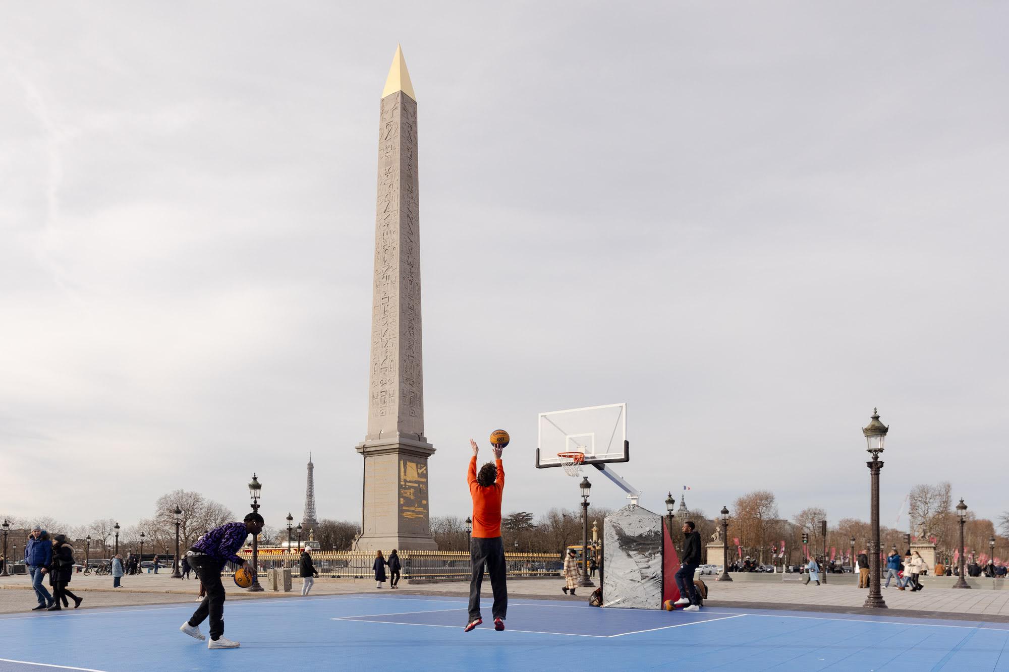 Parisiens s'essayant au basket sur le terrain du Concorde Park avec l'obélisque en fond. 