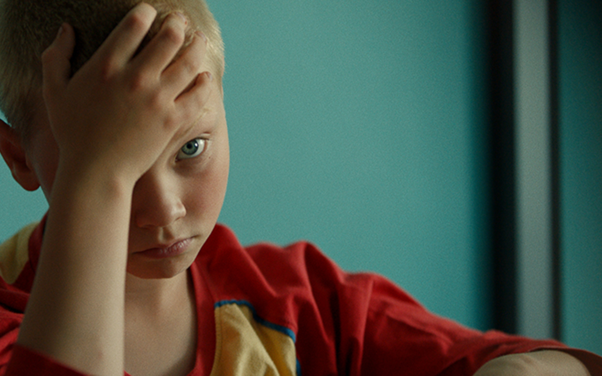 Petit garçon qui semble triste et qui prend sa tête dans ses mains
