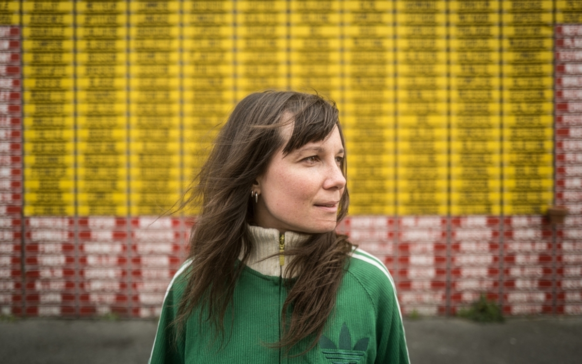 jeune femme en blouson vert photographiée sur fonds de rue