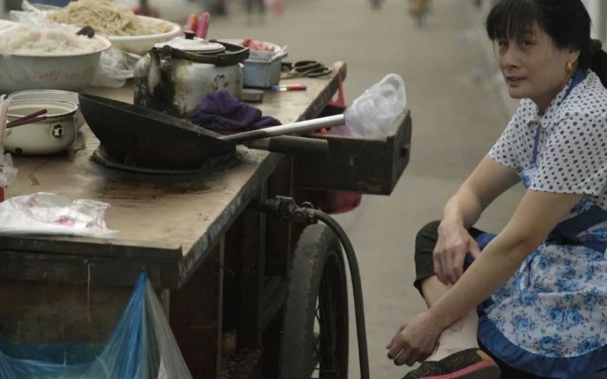 Une femme asiatique devant un étal dans une rue passante