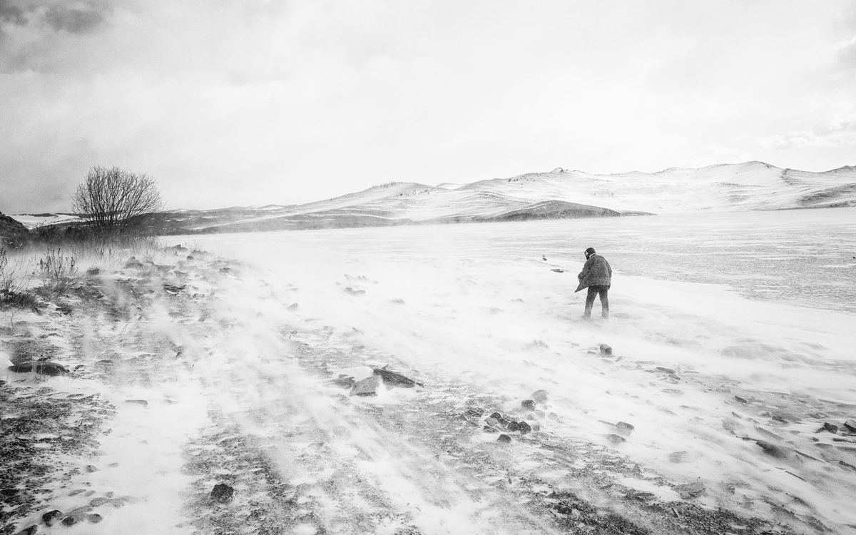 photographie noir et blanc d'un homme en Russie dans un paysage gigantesque désertique enneigé