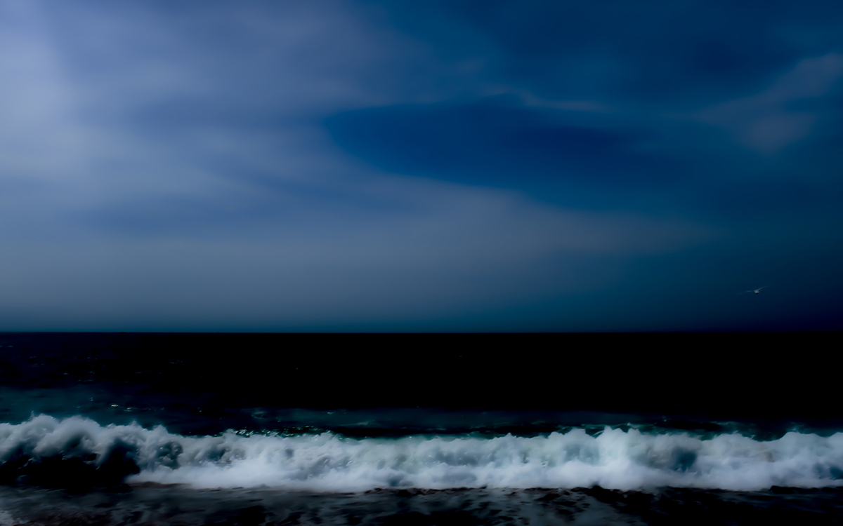 Photo représentant une vague qui se confond avec un ciel sombre 