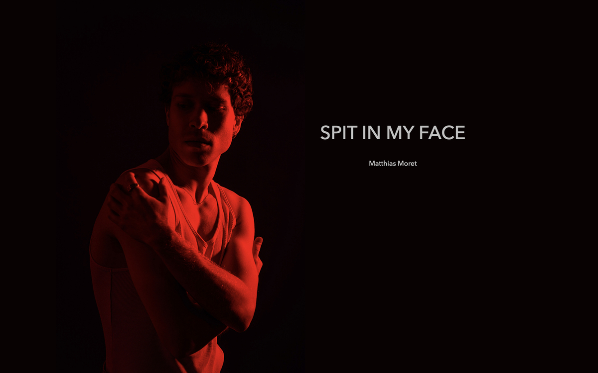 Photo d'un homme les bras autour de son corps, une lumière rouge sur lui, sur fond noir. titre du spectacle à droite de la tête