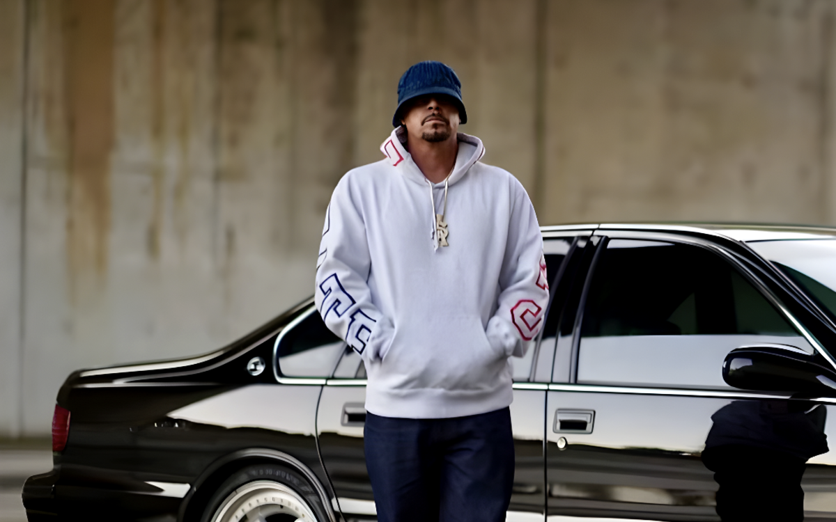 Photo de DJ Muggs debout devant une voiture noire