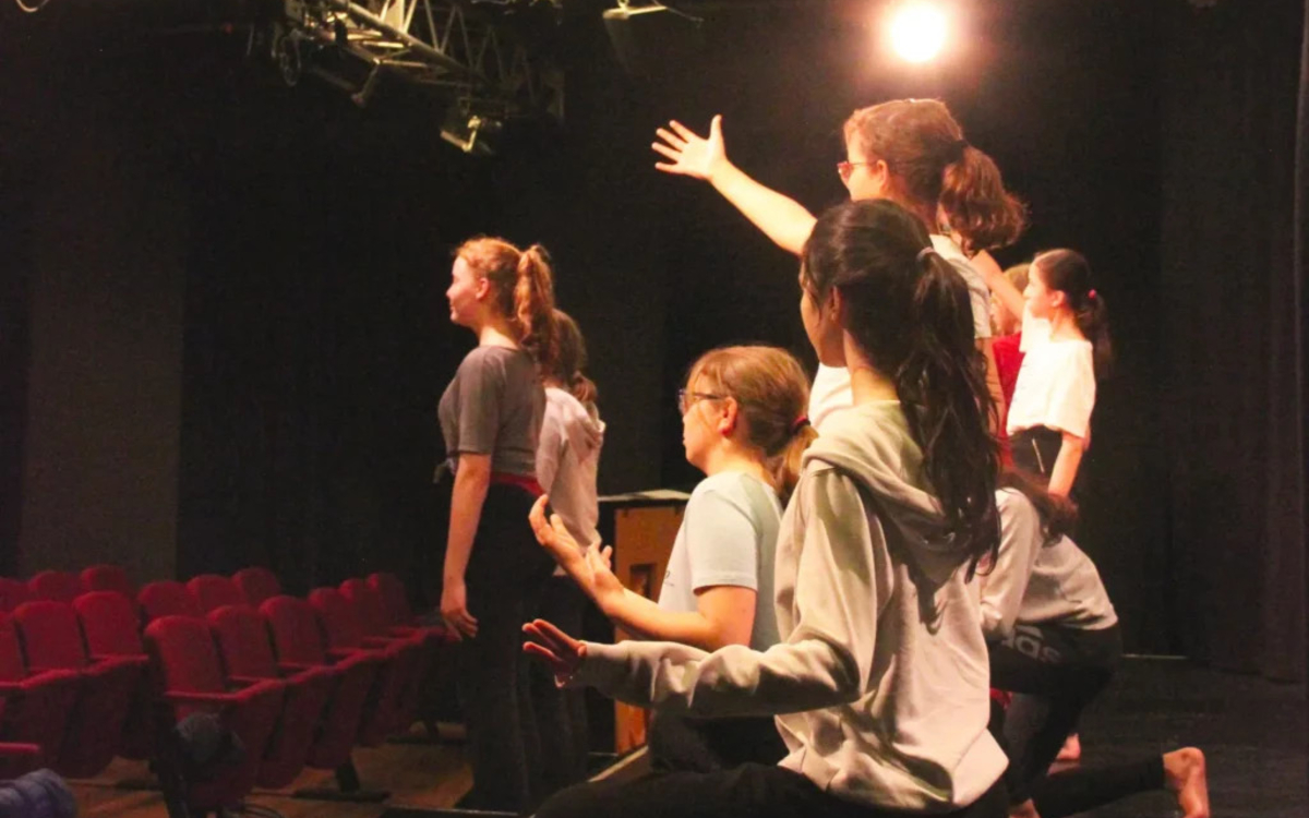 enfants faisant le salut sur le devant de la scène de théâtre. On ne voit pas leur visages