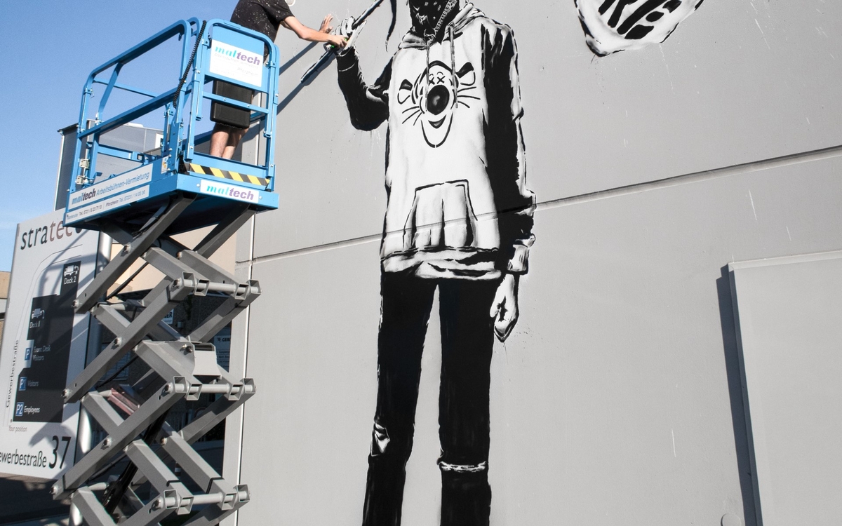 Graphe géant sur un mur d'immeuble représentant une adolescente masquée et tenant un drapeau sur l'épole sur lequel est inscrit "Go futur", signifiant l'engagement de la jeunesse pour un futur positif.