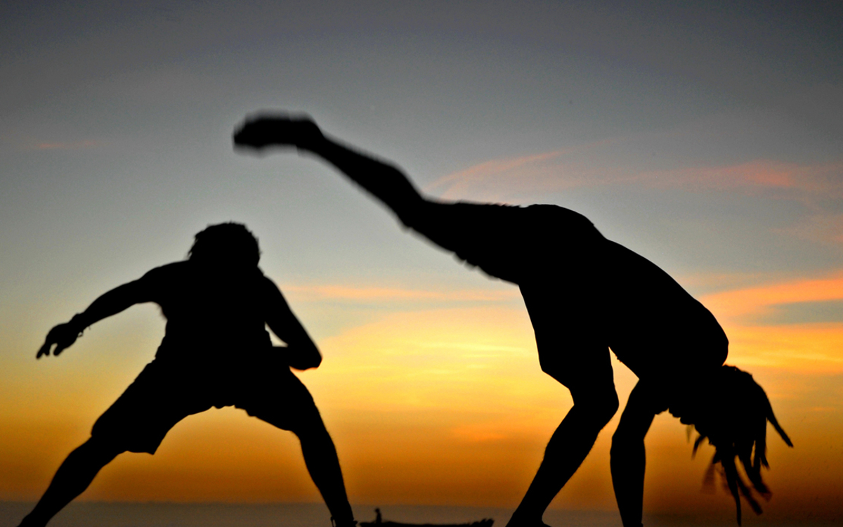 Séance de capoeira sur fond de coucher de soleil. 