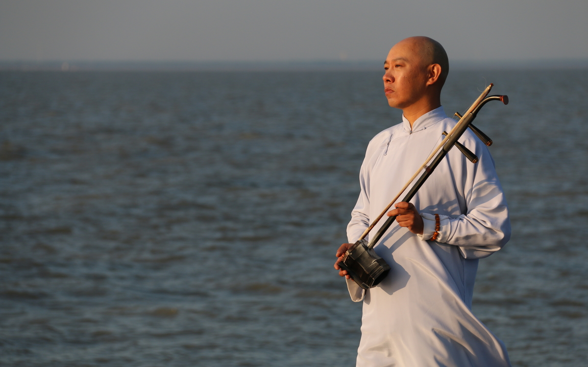 Le musicien Guo Gan, tenant son erhu devant la mer