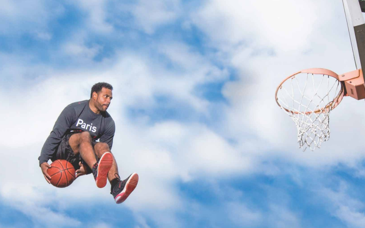Un homme saute dans les airs et tente de mettre un panier