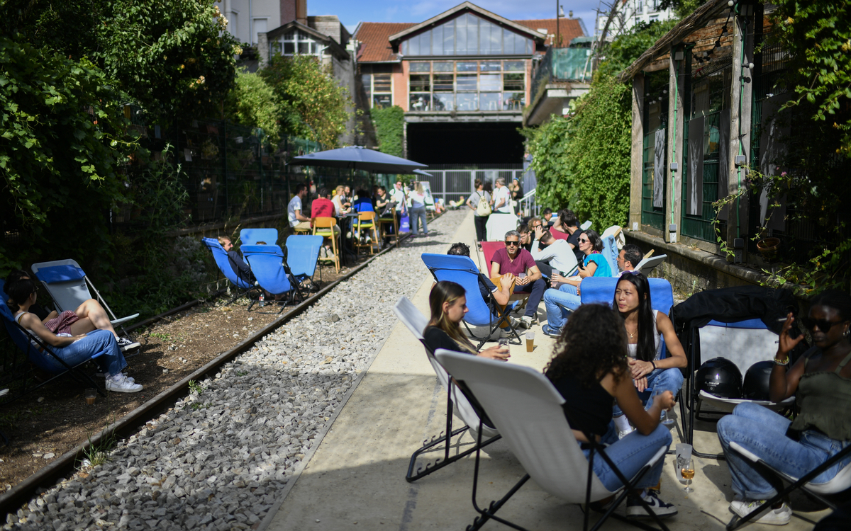 Personnes assises dans des transats bleus le long des rails de la Recyclerie