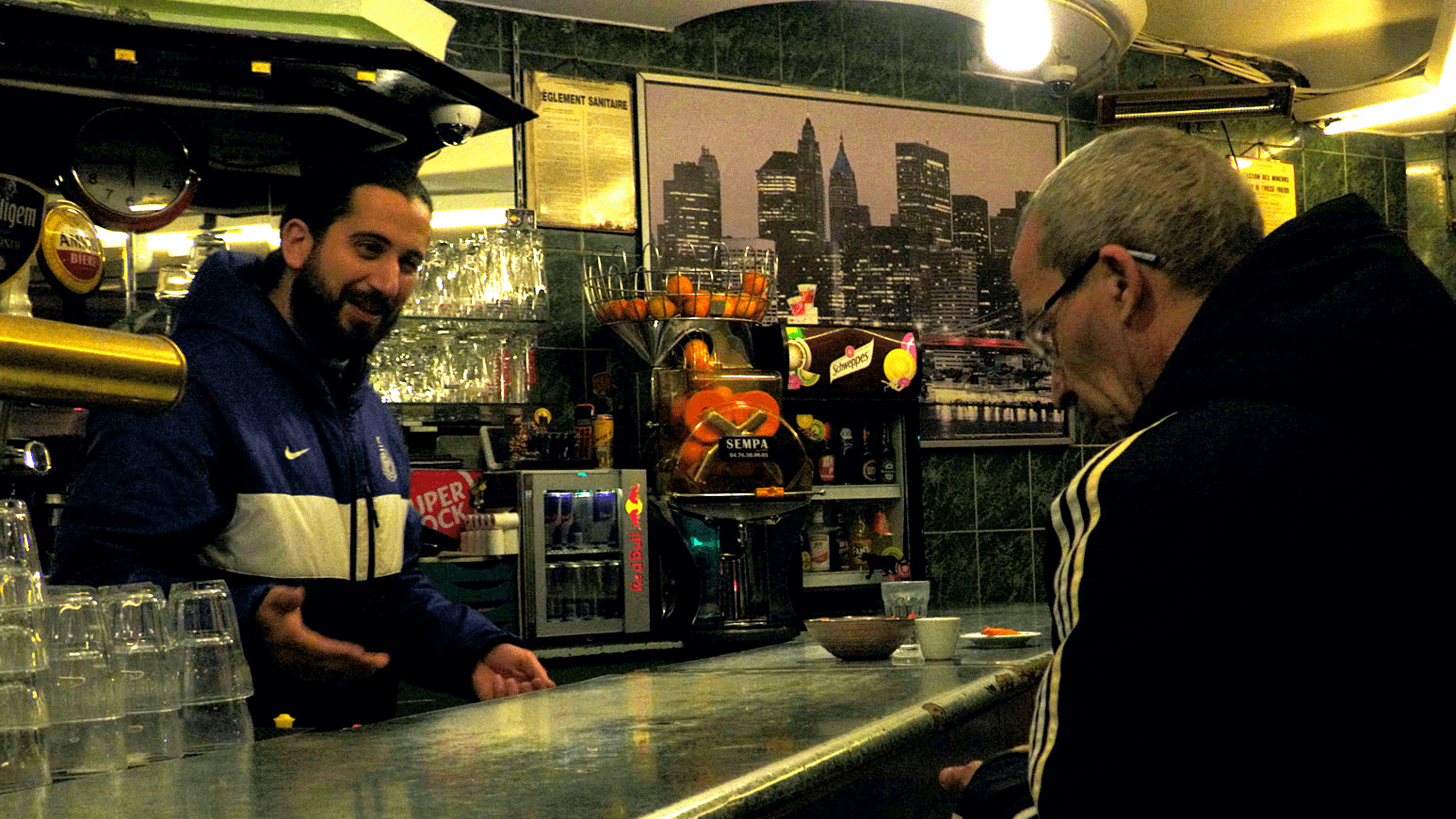 ateliers varan - image extraite d'un film réalisé à Aubervilliers - on y voit un tenancier de bar discuter avec un client au petit matin