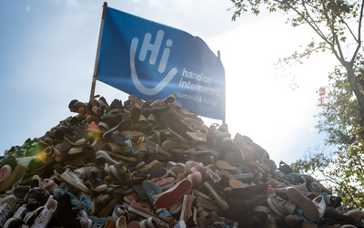 Un bénévole de Handicap International, lance une paire de chaussures sur la Pyramide de chaussures.