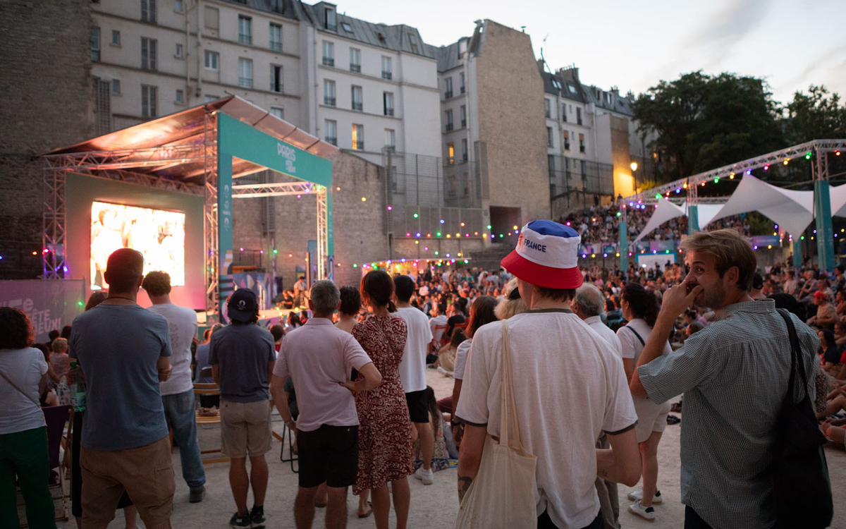 Vue de dos de la foule présente aux Arènes de Lutèce alors que le soleil se couche