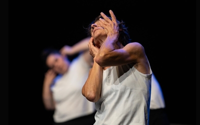 Photo issue du spectacle «ABWARTEN» de Yohan Vallée, représentant deux danseuses sur fond noir avec un tee-shirt blanc