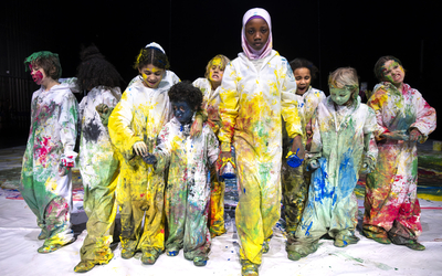 Groupe d'enfants sur scène dans des combinaisons recouvertes de peinture