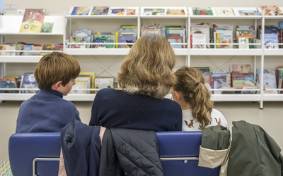 Vue de dos d'une femme lisant un livre à deux enfants