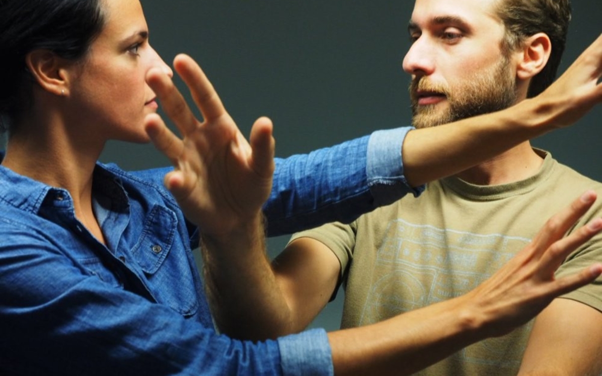Une homme et une femme se font face, les bras entremêlés