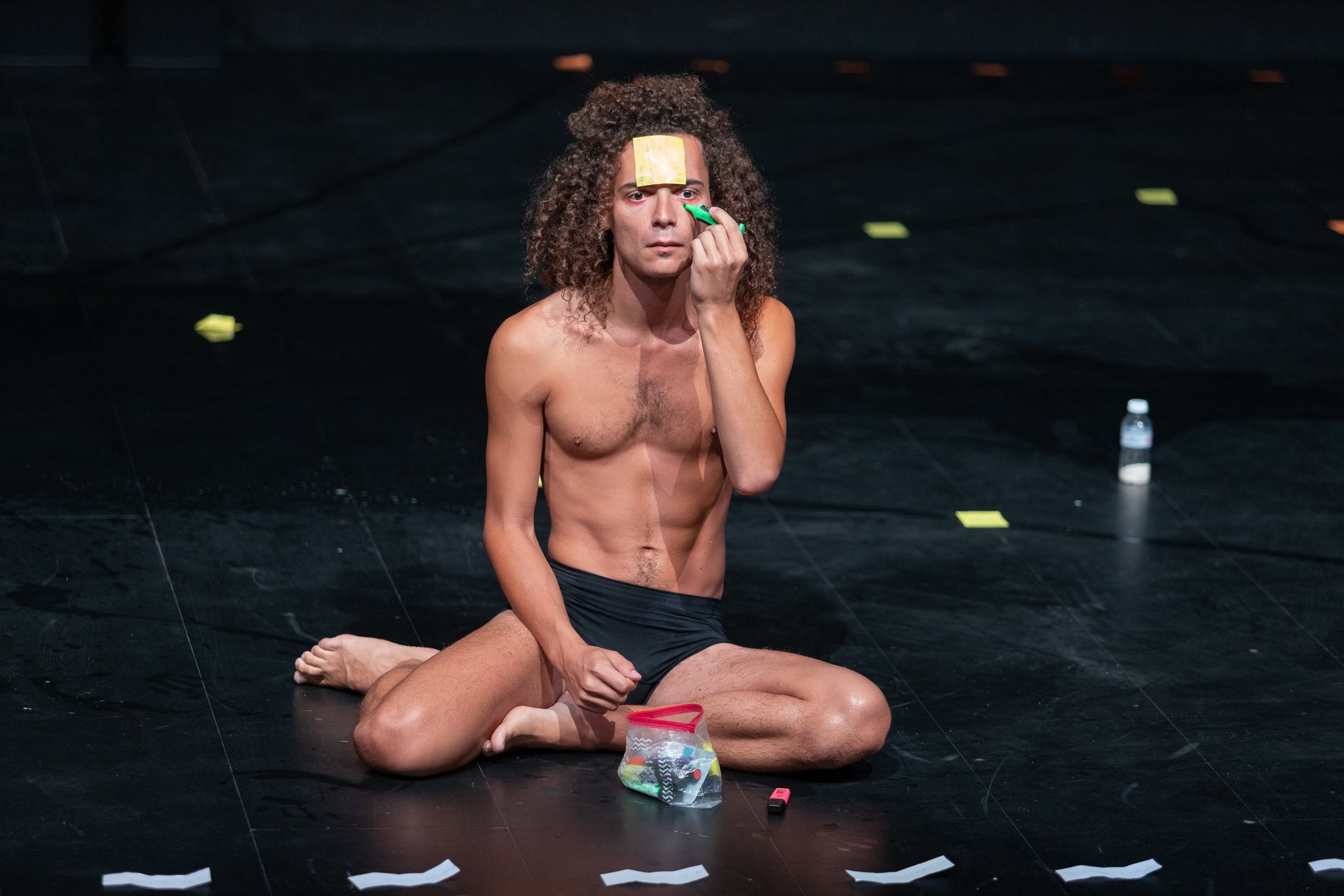 L'acteur est assis sur la scène, un feutre à la main et un post-it collé sur le front.