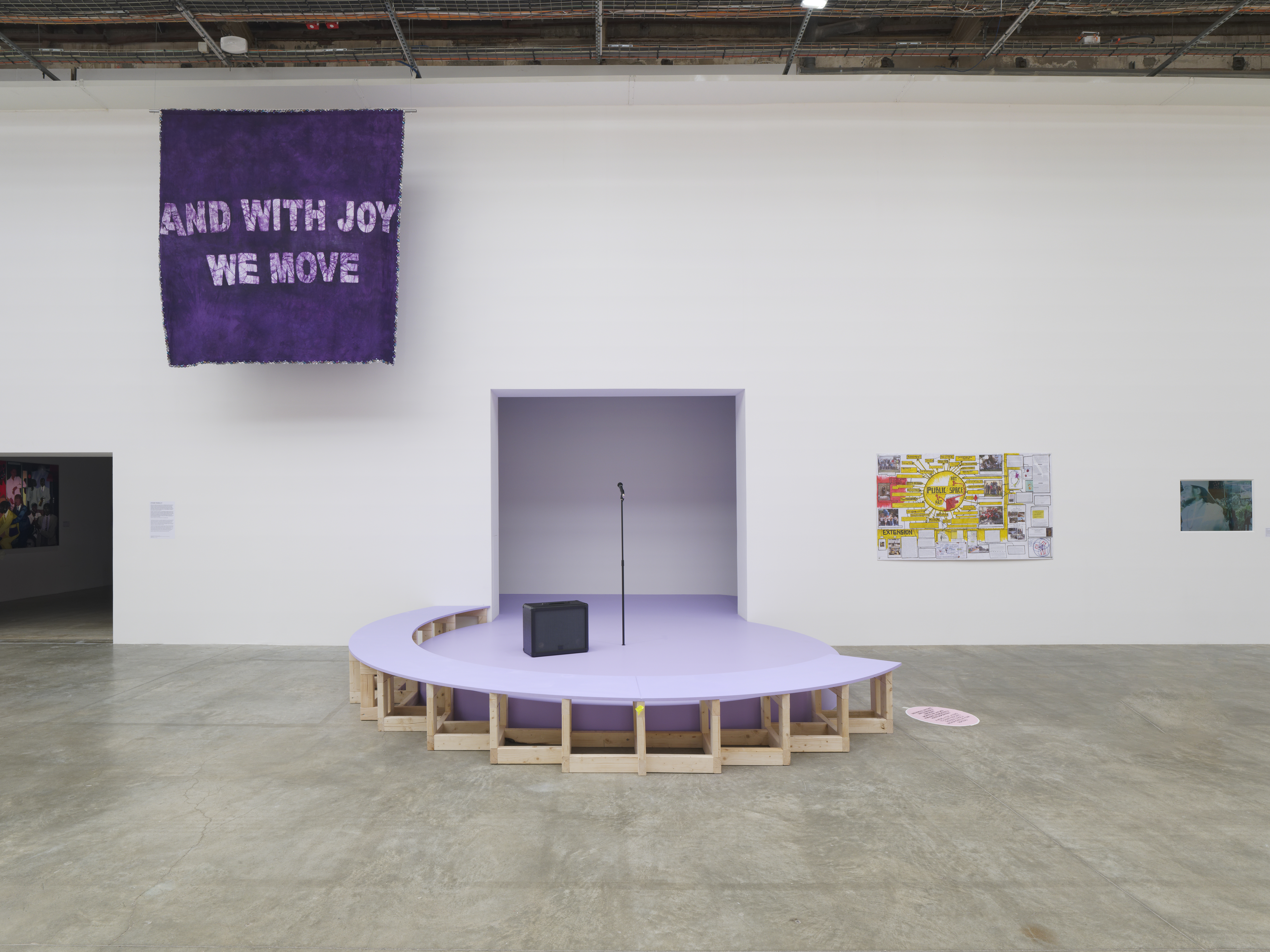 Installation d'une estrade violette avec un micro et une banderole "and with joy we move"