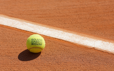 Zoom sur une balle de tennis sur de la terre battue.