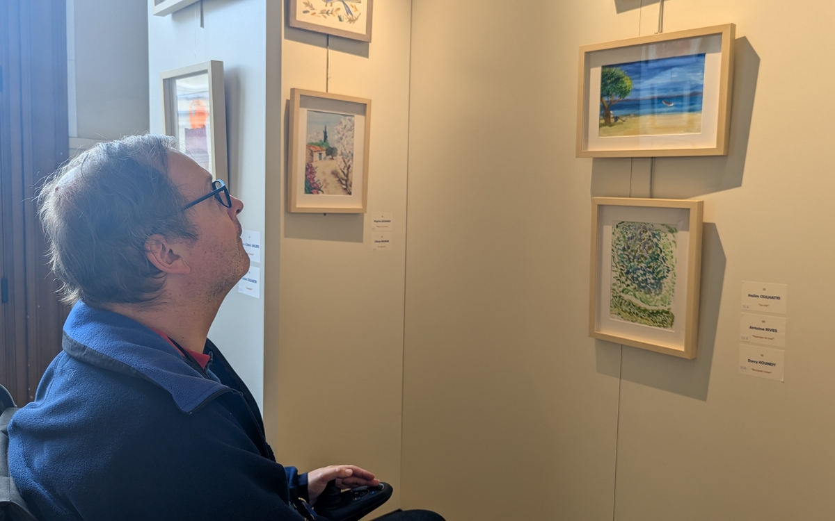 Antoine, l'un des artistes de l'exposition, contemple un des tableaux