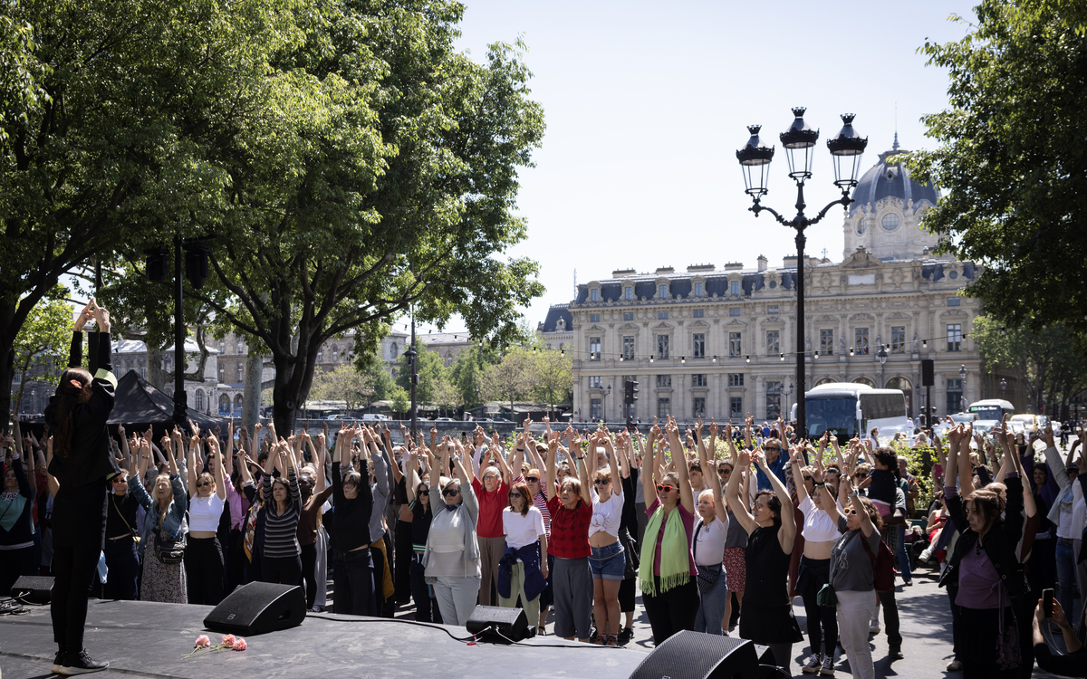 Un danseur sur une estrade en plein Paris exécute des mouvements qu'une petite foule reproduit face à lui