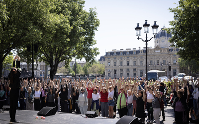 Un danseur sur une estrade en plein Paris exécute des mouvements qu'une petite foule reproduit face à lui