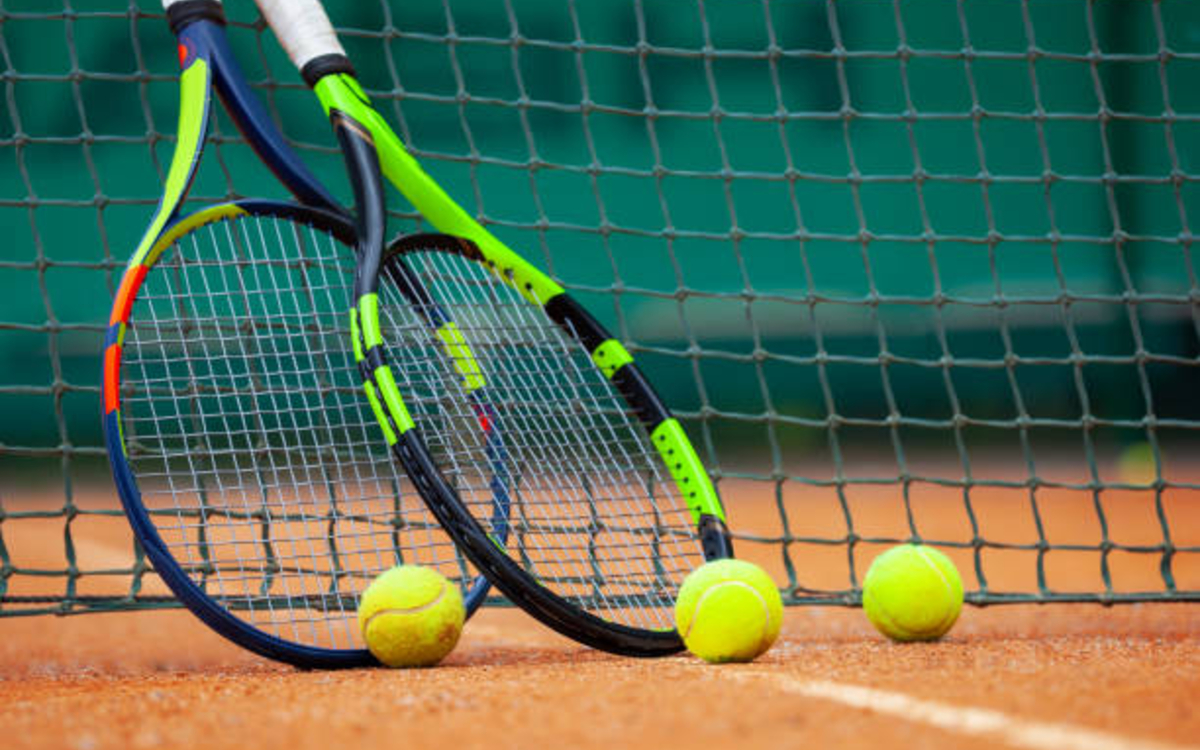 Un court de tennis avec deux raquettes posées contre le filet, avant le début des cours