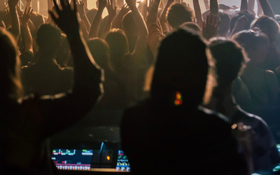 Gens de dos en train de lever les bras dans une salle de concert 