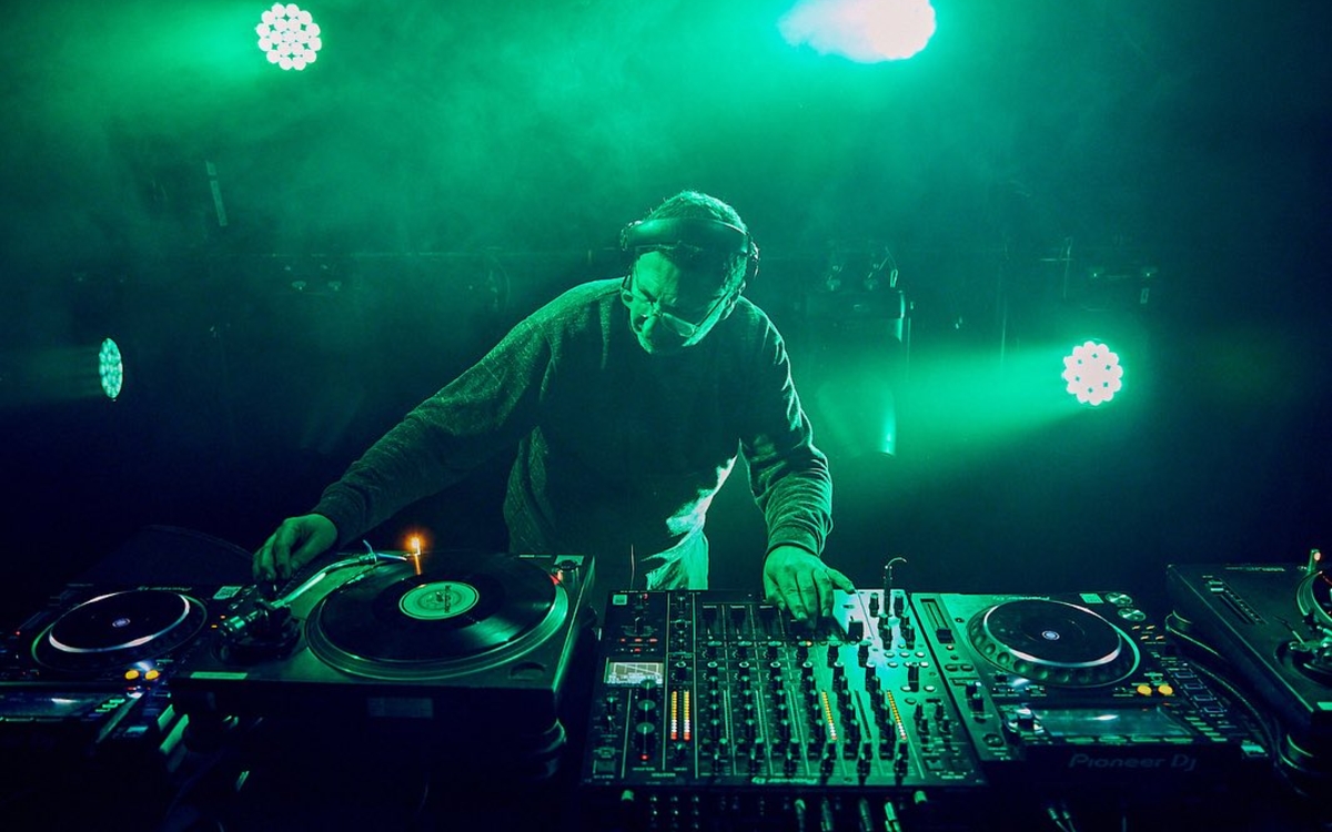 Un DJ derrière les platines, lumières vertes