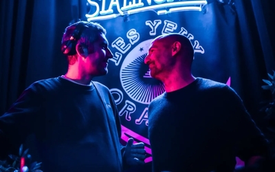 Deux DJs derrière les platines se regardent en souriant