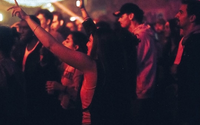 Dans un club, une femme au milieu d'une foule danse les bras levés