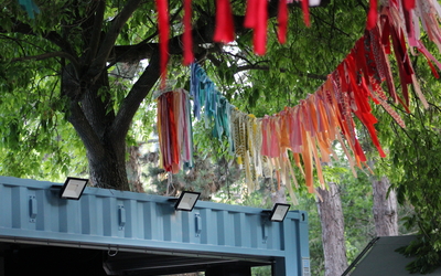 Photographie d'une partie de la Scène Créative de La Guinguette et décorations en nouettes colorées accrochées aux arbres. 