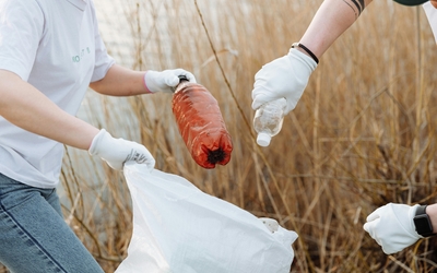 Deux personnes ramassant des déchets en plastique pour les mettre dans un sac poubelle et dépolluer les sols