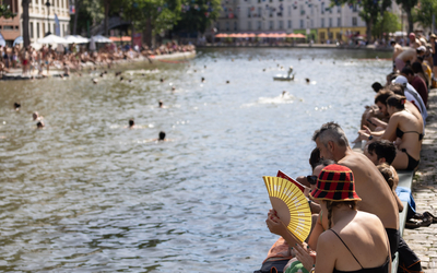 Des personnes profitent d'une journée estivale ensoleillée pour se baigner dans le canal Saint Martin.  