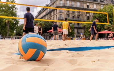 Un ballon posé au sol sur le sable devant un terrain de Beach volley sur le parvis de l'Hôtel de Ville. 