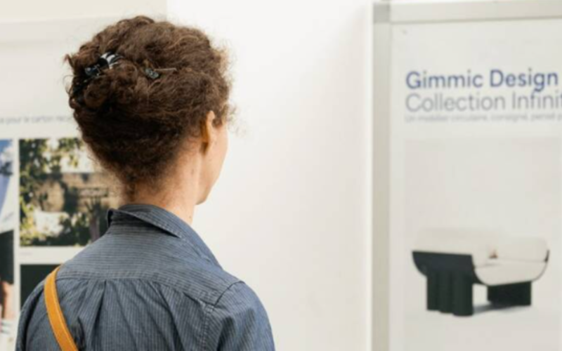 Une femme de dos regarde une oeuvre exposée au mur
