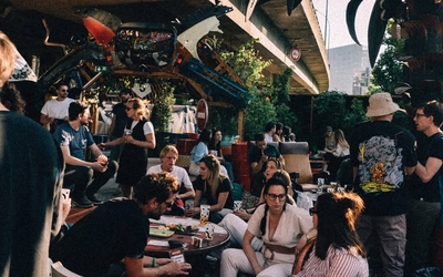 Des gens en train de prendre l'apéro dans un lieu en plein air sous le périphérique