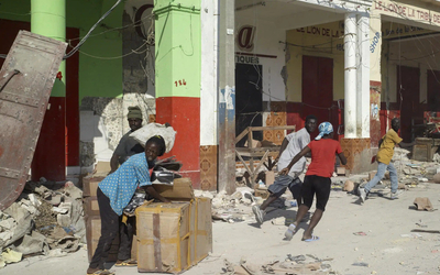 Des hommes et des femmes pillent une ville qui semble tombée dans le chaos