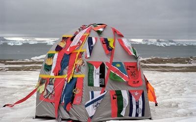 Une tente recouverte de plusieurs drapeaux au milieu d'un paysage montagneux