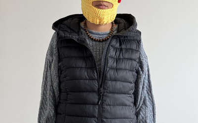 Une comédienne se tient seule, elle  nous regarde, avec n masque tricoté du pokémon Pikachu (petite créature jaune aux joues rouges et aux oreilles très pointues)