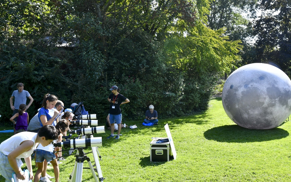 un groupe d'enfants utilisant des lunettes astronomiques, à côté d'une lune gonflable